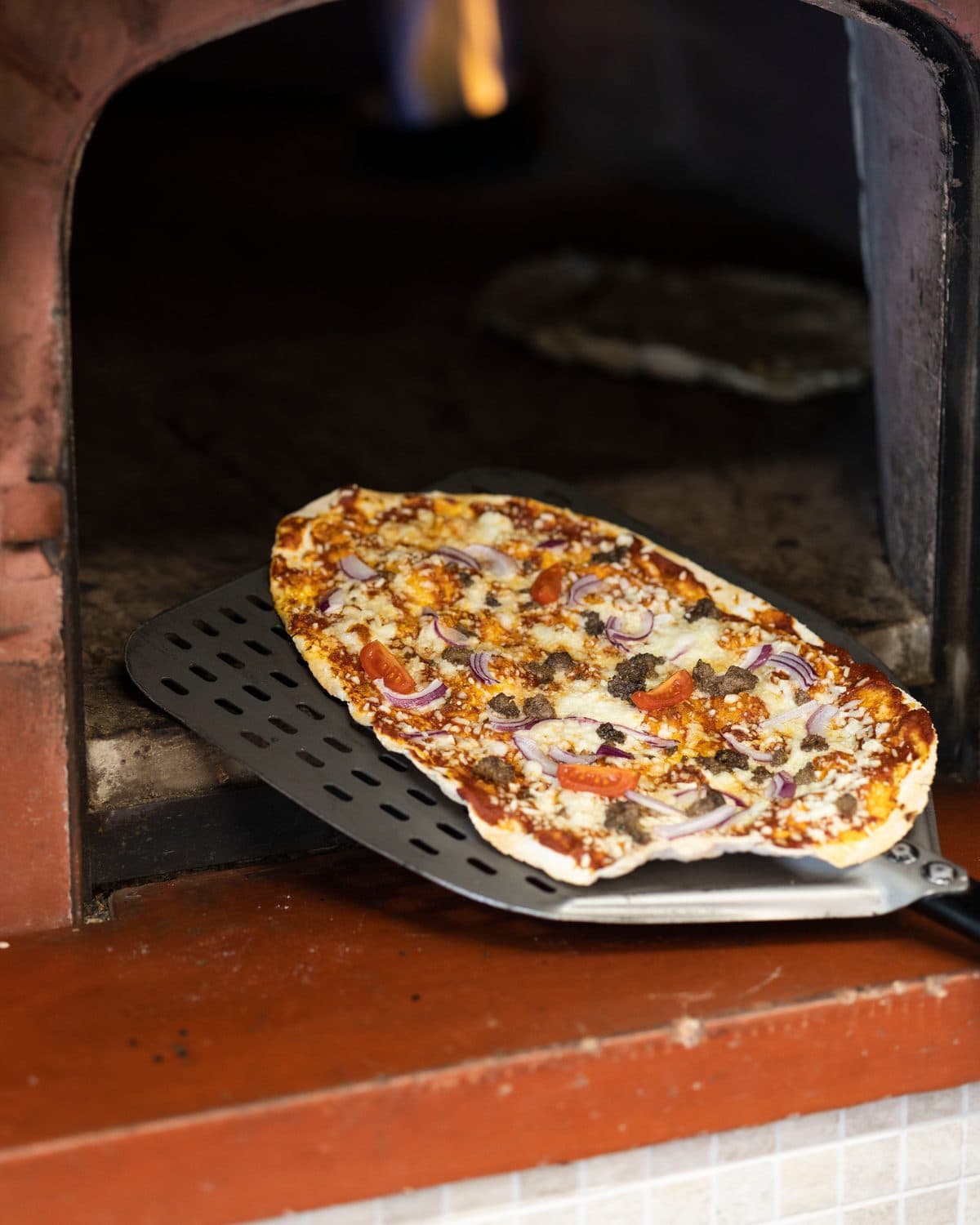 Pizza på takkesteikt botn i vedomnen i kafeen